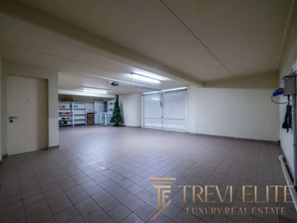 Большой просторный гараж с белыми стенами и просторной зоной для хранения автомобилей.