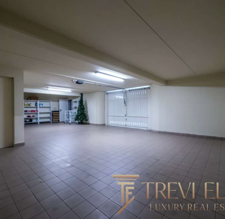 Большой просторный гараж с белыми стенами и просторной зоной для хранения автомобилей.