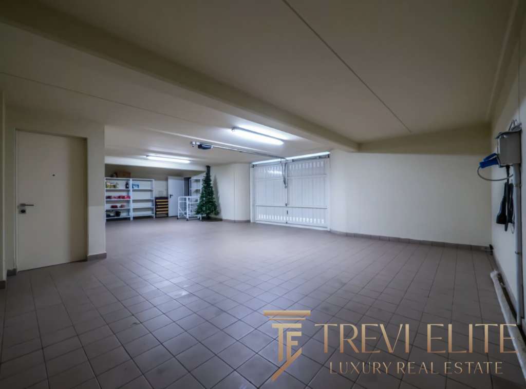 Большой просторный гараж с белыми стенами и просторной зоной для хранения автомобилей.