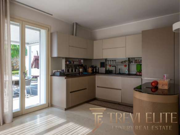 Современная светлая кухня с выходом на уютную террасу, идеально подходящая для отдыха и готовки в элитной недвижимости.