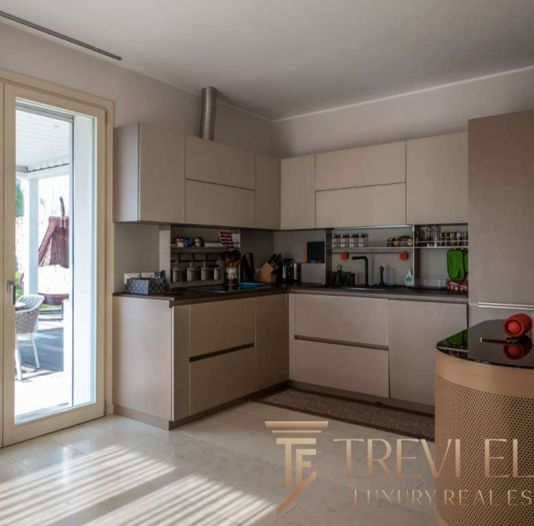 Современная светлая кухня с выходом на уютную террасу, идеально подходящая для отдыха и готовки в элитной недвижимости.