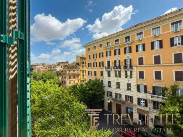 Высокий ракурс на классический жилой дом в центре Рима с зелеными деревьями и ярким голубым небом, демонстрирующий элитную недвижимость для клиентов Trévi Élite.