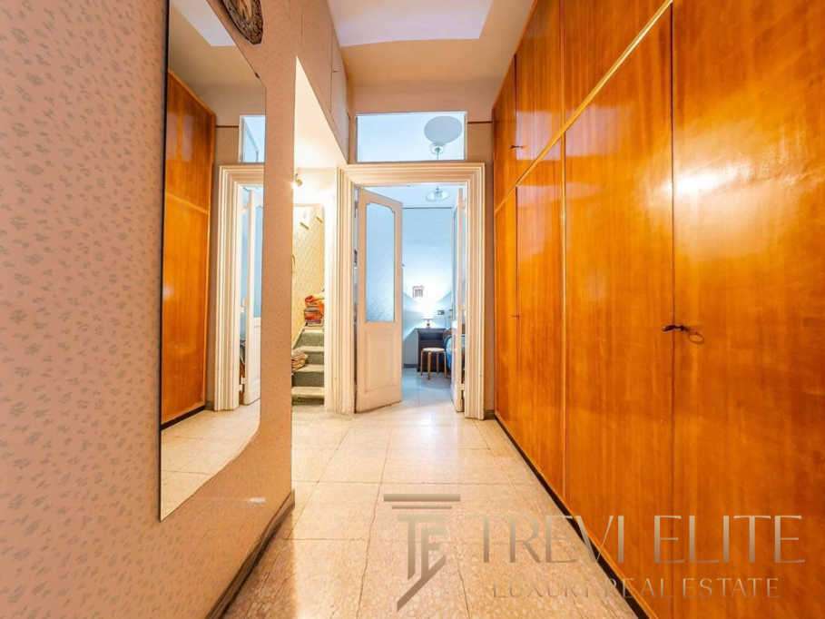 Входная зона квартиры с деревянными шкафами и зеркалом, уютный коридор, ведущий в гостиную и спальню, элегантный интерьер, создающий атмосферу роскоши и комфорта.