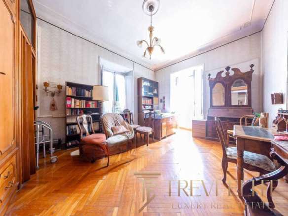 Элегантная гостиная с деревянной мебелью, ярким светом и антикварными предметами, создающая атмосферу уюта и классического стиля в высококлассной недвижимости.