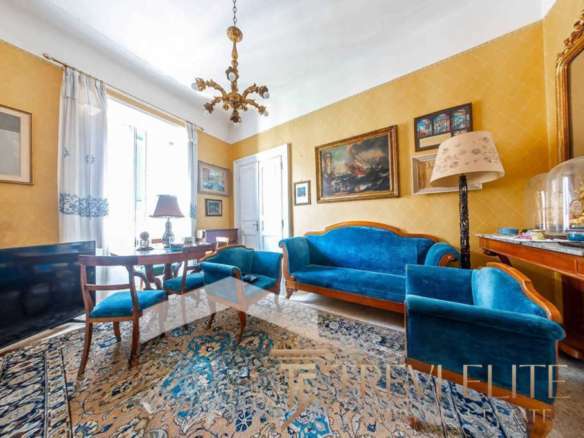 Роскошная гостиная в элитном доме с классической мебелью, яркими картинами и светлым интерьером в стиле английский стиль, украшенная богатым ковром и оригинальной люстрой.