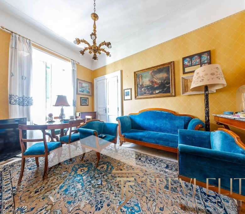 Роскошная гостиная в элитном доме с классической мебелью, яркими картинами и светлым интерьером в стиле английский стиль, украшенная богатым ковром и оригинальной люстрой.
