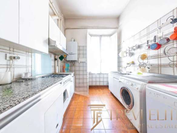 Богатая кухня в уютной квартире с белыми шкафами и стиральной машиной, яркие чашки и посуда в современном стиле, просторное освещенное помещение с окнами и теплым полом.