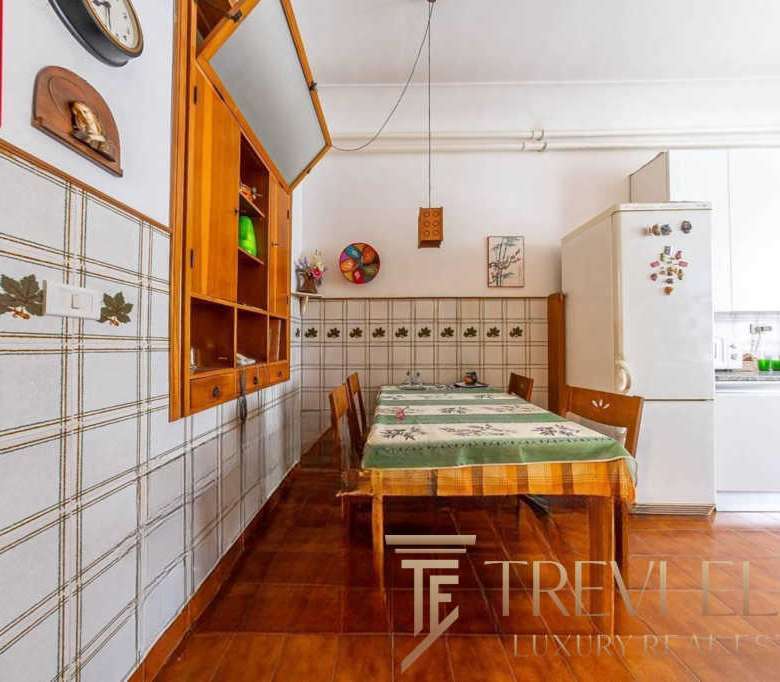 Кухня с деревянной мебелью и кафельной отделкой, уютное пространство для семейных обедов, светлые стены и современная техника, идеально подходит для проживания высокого класса.