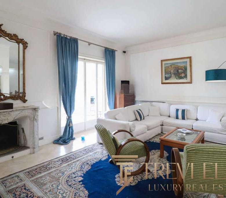 Элегантная гостиная в роскошной квартире с камином, белыми стенами и классической мебелью, украшенной искусственным освещением и уютным интерьером в стиле высокого класса.