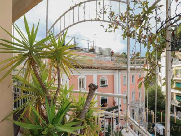 Высокий балкон с зелеными садовыми растениями и видом на роскошные апартаменты в стиле итальянской классики. Идеальное место для отдыха и наслаждения городским пейзажем.