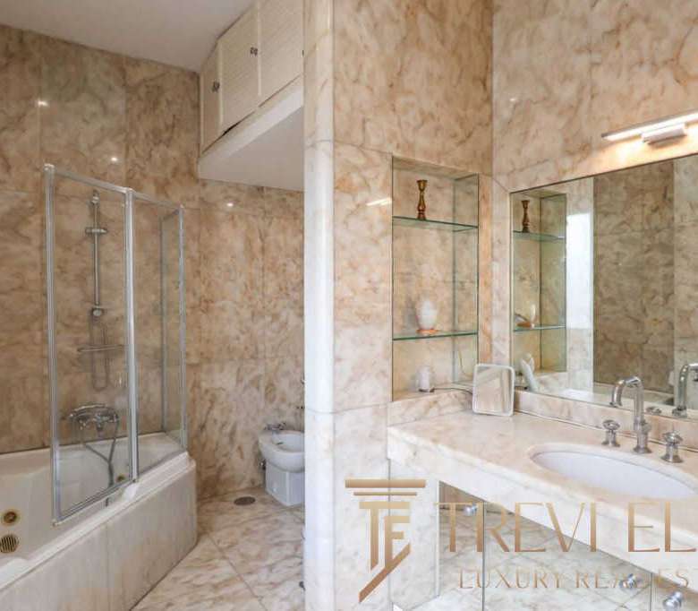 Роскошная ванная комната с мраморной отделкой, современной сантехникой и просторной системой душа. Элитный дизайн подчеркивает комфорт и стиль высокого уровня недвижимости.