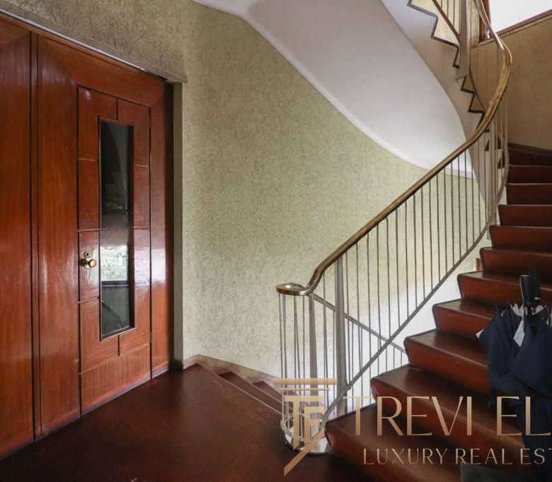 Современная деревянная дверь и кованая лестница в роскошном интерьере элитного дома. Идеальное решение для тех, кто ценит комфорт и стиль в недвижимости.