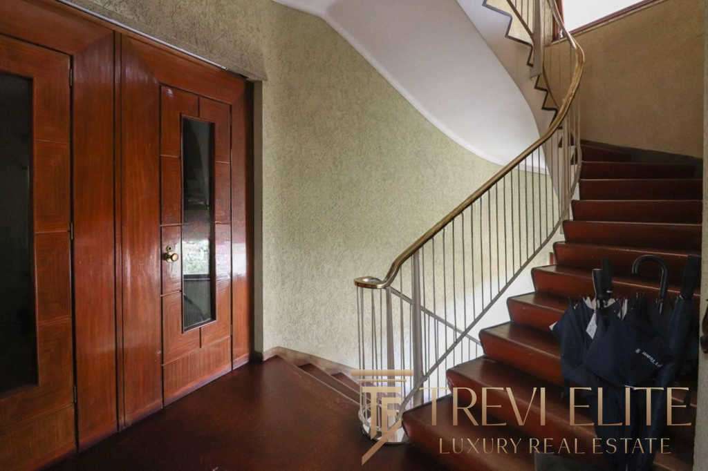 Современная деревянная дверь и кованая лестница в роскошном интерьере элитного дома. Идеальное решение для тех, кто ценит комфорт и стиль в недвижимости.