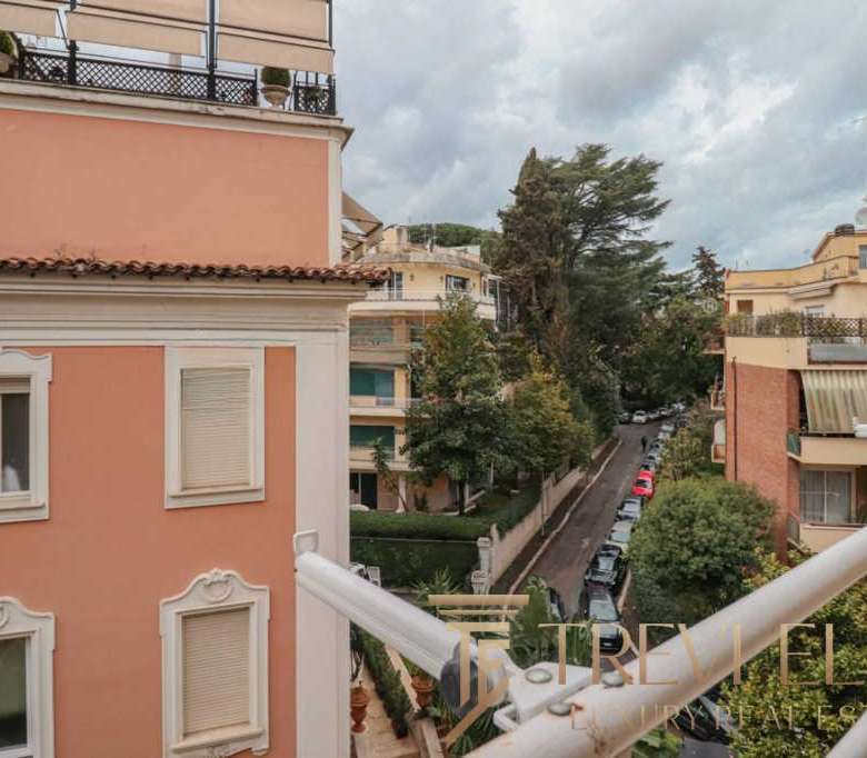 Элегантный вид на жилой район с уютными многоэтажками, зеленью и городской уличной жизнью, идеально передающий атмосферу приватности и престижности элитной недвижимости в Италии.