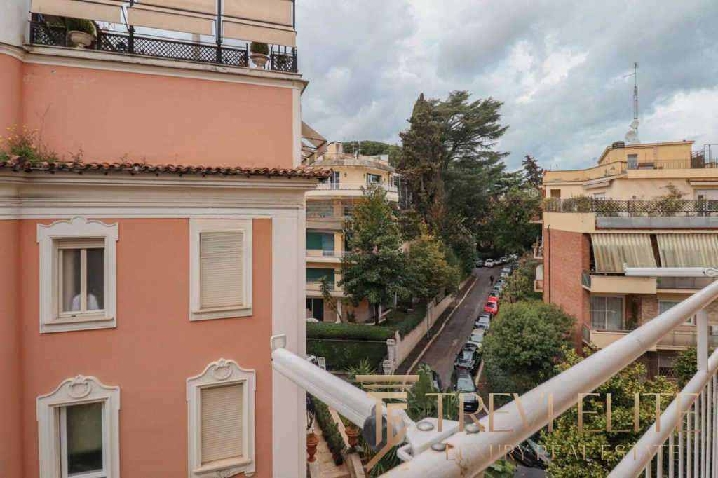 Элегантный вид на жилой район с уютными многоэтажками, зеленью и городской уличной жизнью, идеально передающий атмосферу приватности и престижности элитной недвижимости в Италии.