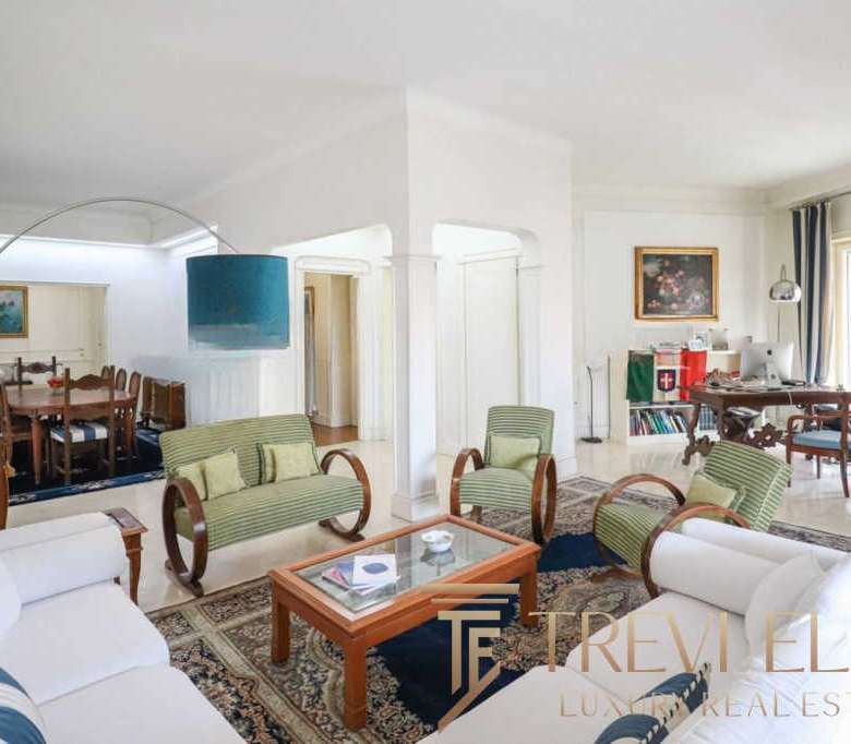 Уютная гостиная с мягкими диванами и креслами, светлые стены и большие окна создают атмосферу роскоши и комфорта в элитной недвижимости.