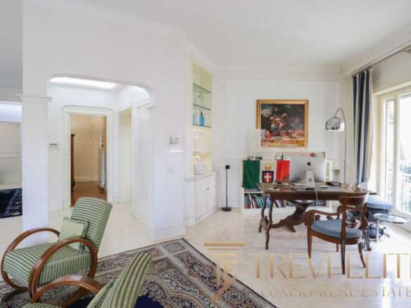 Уютный интерьер светлой квартиры с большим рабочим столом, книжными полками и панорамными окнами на балкон. Элегантный дизайн и комфорт создают атмосферу роскоши и уюта.