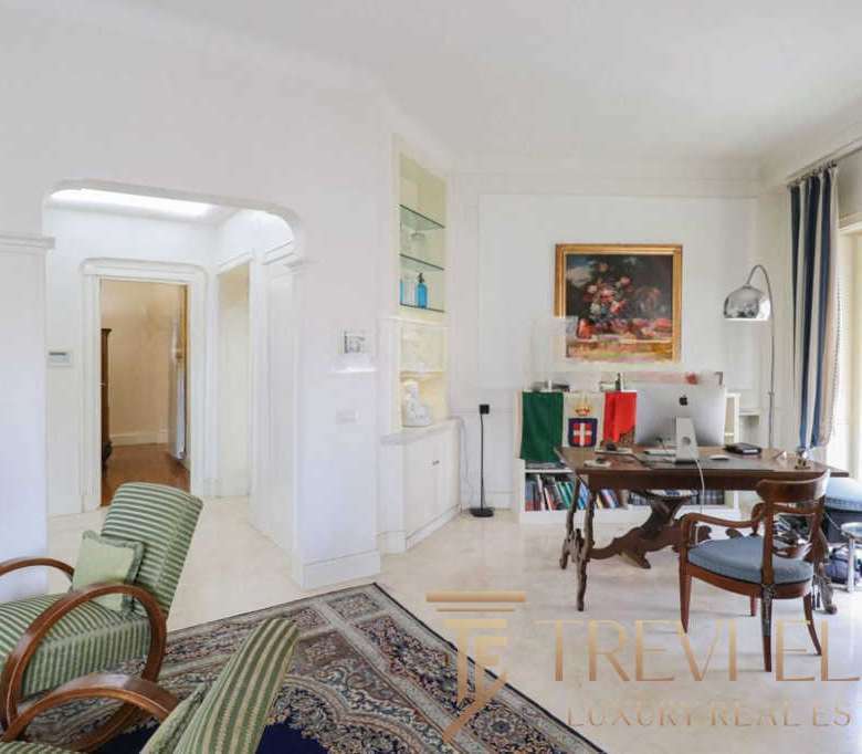 Уютный интерьер светлой квартиры с большим рабочим столом, книжными полками и панорамными окнами на балкон. Элегантный дизайн и комфорт создают атмосферу роскоши и уюта.