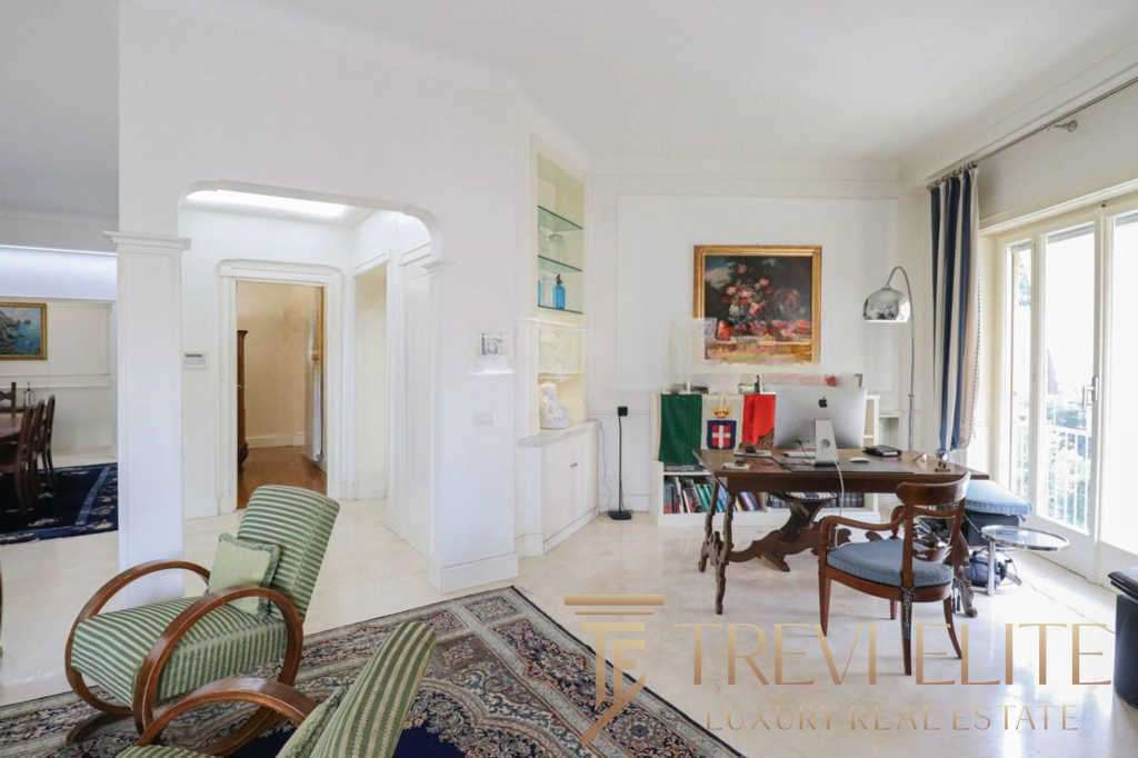 Уютный интерьер светлой квартиры с большим рабочим столом, книжными полками и панорамными окнами на балкон. Элегантный дизайн и комфорт создают атмосферу роскоши и уюта.