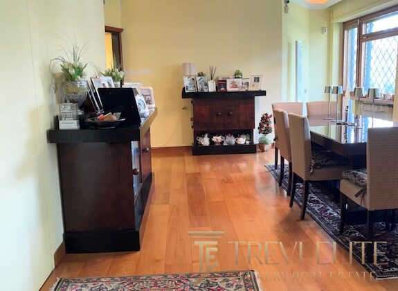 Комфортная гостиная с мебелью, большим окном и деревянным полом, идеально подходящая для отдыха и приема гостей. Высококлассный интерьер, создающий уют и стильное впечатление.