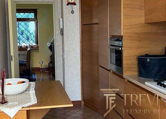 Современная кухонная зона в элитной недвижимости, выполненная из натурального дерева, с современными бытовыми приборами и уютным интерьером. Отличное пространство для комфортной жизни и приема гостей.