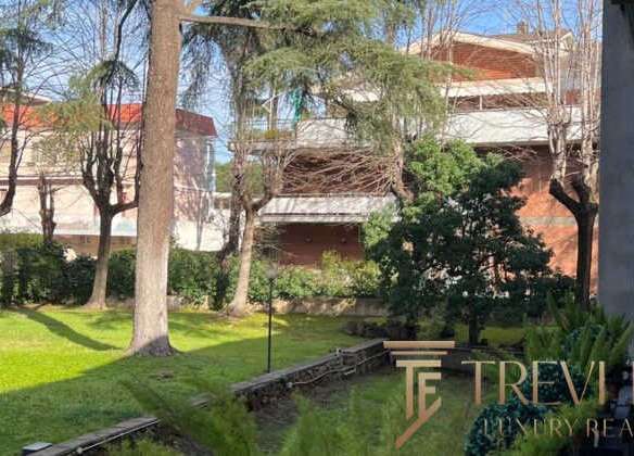 Современный зеленый сад с деревьями и ухоженной травой, рядом с элитным жилым комплексом и уютной зоной отдыха, предложение эксклюзивной недвижимости от агентства Треви Элит.