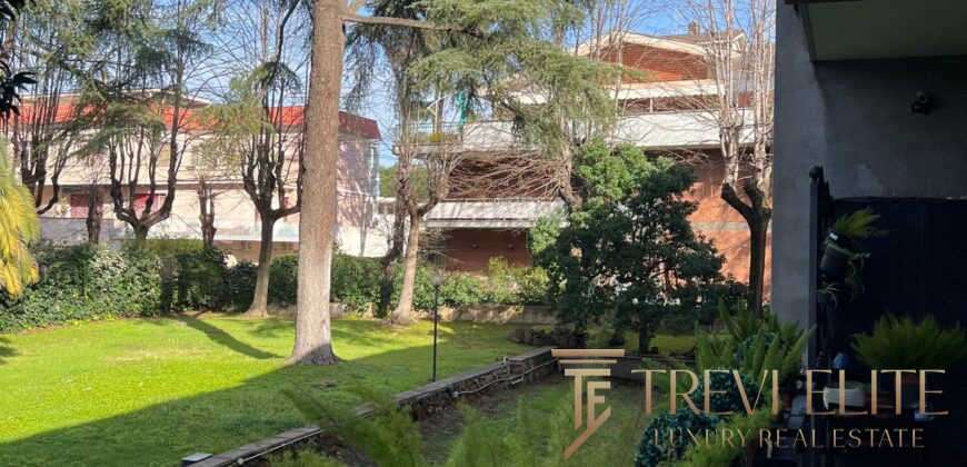 Современный зеленый сад с деревьями и ухоженной травой, рядом с элитным жилым комплексом и уютной зоной отдыха, предложение эксклюзивной недвижимости от агентства Треви Элит.