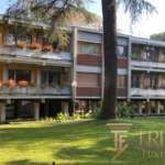 Элитный жилой дом на фоне зеленого сада с деревьями и ухоженной территорией, демонстрирующий роскошную недвижимость в премиум-классе для клиентов Trevi Elite.