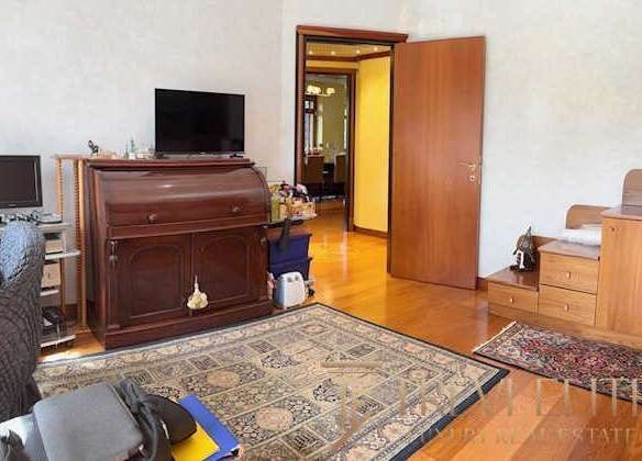 Уютная гостиная с деревянной мебелью, телевизором и мягким креслом, оформление классического интерьера, деревянные полы и декоративные ковры создают приятную атмосферу дома.