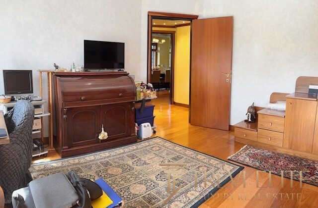 Уютная гостиная с деревянной мебелью, телевизором и мягким креслом, оформление классического интерьера, деревянные полы и декоративные ковры создают приятную атмосферу дома.