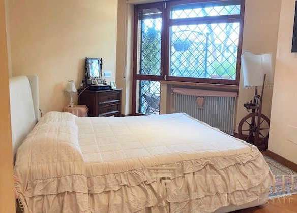 уютная спальня с большим окном и классической мебелью, идеально подходящая для роскошной недвижимости en Италии и мира, предлагается агентством Треви Элит.