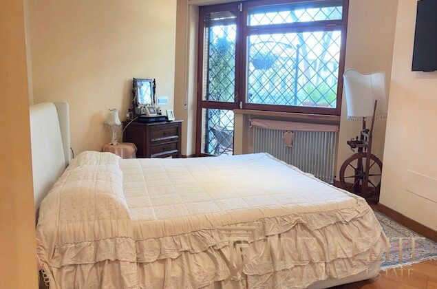 уютная спальня с большим окном и классической мебелью, идеально подходящая для роскошной недвижимости en Италии и мира, предлагается агентством Треви Элит.