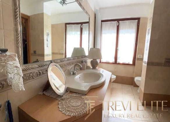 Разделанная ванная комната с большим зеркалом, раковиной и красивыми деталями интерьера в элитной недвижимости. Идеальное пространство для роскошного отдыха и уединения.