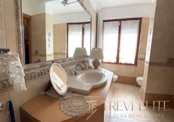 Разделанная ванная комната с большим зеркалом, раковиной и красивыми деталями интерьера в элитной недвижимости. Идеальное пространство для роскошного отдыха и уединения.