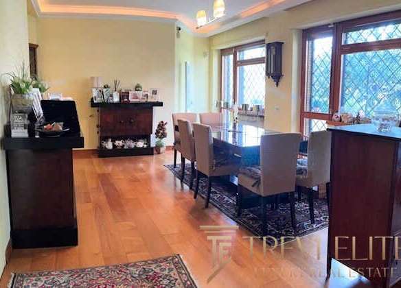 Оффтоповая гостиная с большими окнами, уютным интерьером и просторной зоной для приема гостей, идеально подходящей для элитной недвижимости.