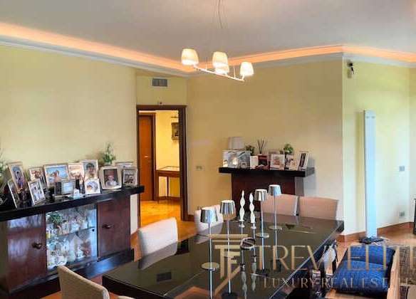 Современная роскошная гостиная с элегантной мебелью, декоративными свечами и семейными фотографиями на фоне светлых стен и мягкого освещения.