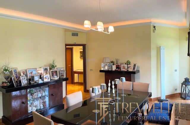 Современная роскошная гостиная с элегантной мебелью, декоративными свечами и семейными фотографиями на фоне светлых стен и мягкого освещения.