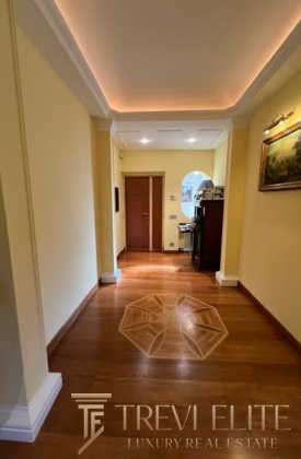 Современный интерьер коридора в элитной недвижимости, светлый дизайн, деревянный пол с уникальной вставкой, мягкое освещение и уютная атмосфера.