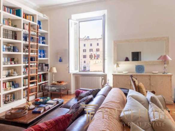 Элегантная гостиная с уютным диваном, книжной полкой и светлым интерьером в современном жилом пространстве.