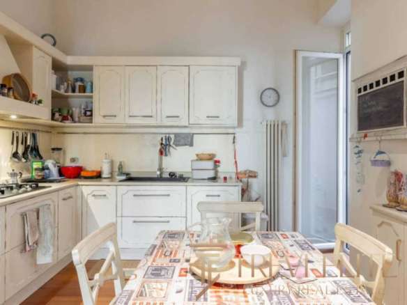 Уютная кухня в светлых тонах с современной мебелью и яркими декоративными элементами, создающая теплую хозяйственную атмосферу и комфорт для семейных обедов и завтраков.