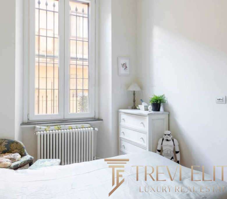 Высококлассная недвижимость в Италии, элегантная спальня с большим окном и классической мебелью, идея для ценителей роскошных интерьеров и эксклюзивных предложений от агентства Треви Элит.