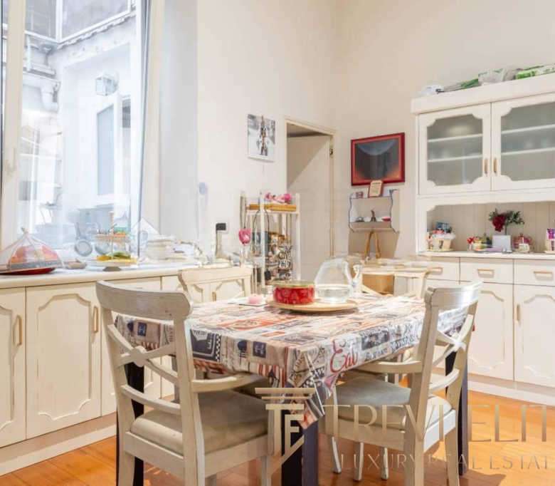 Уютная кухня с большим столом, обставленная в светлых нейтральных тонах, идеальное место для семейных обедов и встреч с друзьями, яркое и гармоничное пространство.