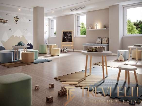 Уютная детская комната с мягкими сиденьями, игровой доской и яркой стеной с горным пейзажем, создающая теплую и безопасную атмосферу для малышей.