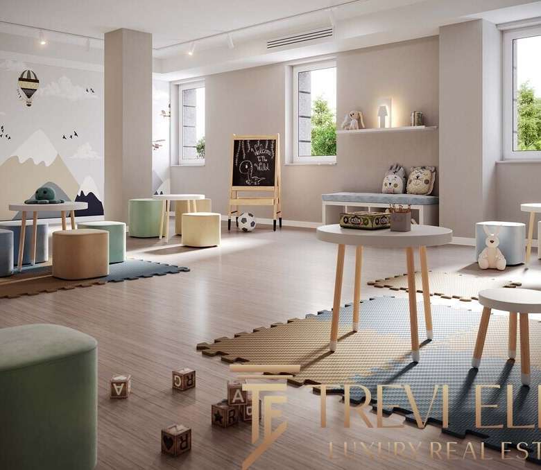 Уютная детская комната с мягкими сиденьями, игровой доской и яркой стеной с горным пейзажем, создающая теплую и безопасную атмосферу для малышей.