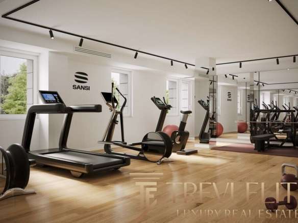 Современный фитнес-зал в элитном жилом комплексе с тренажёрами и зоной для йоги, просторная комната с большим количеством естественного света и стильным дизайном.