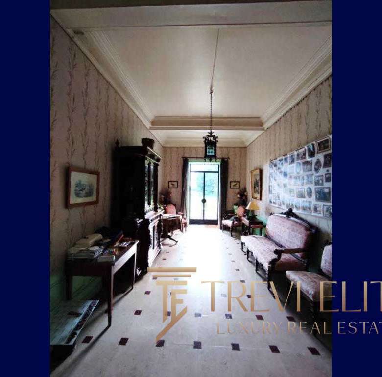 Элегантная гостиная в классическом стиле с антикварной мебелью, картинами на стенах и большим окном, наполняющим комнату естественным светом.