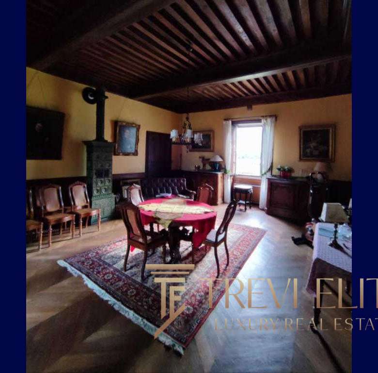 Уютная классическая гостиная в интерьере с деревянной отделкой, камином и антикварной мебелью, создающая атмосферу уюта и роскоши, идеальная для ценителей элитной недвижимости.