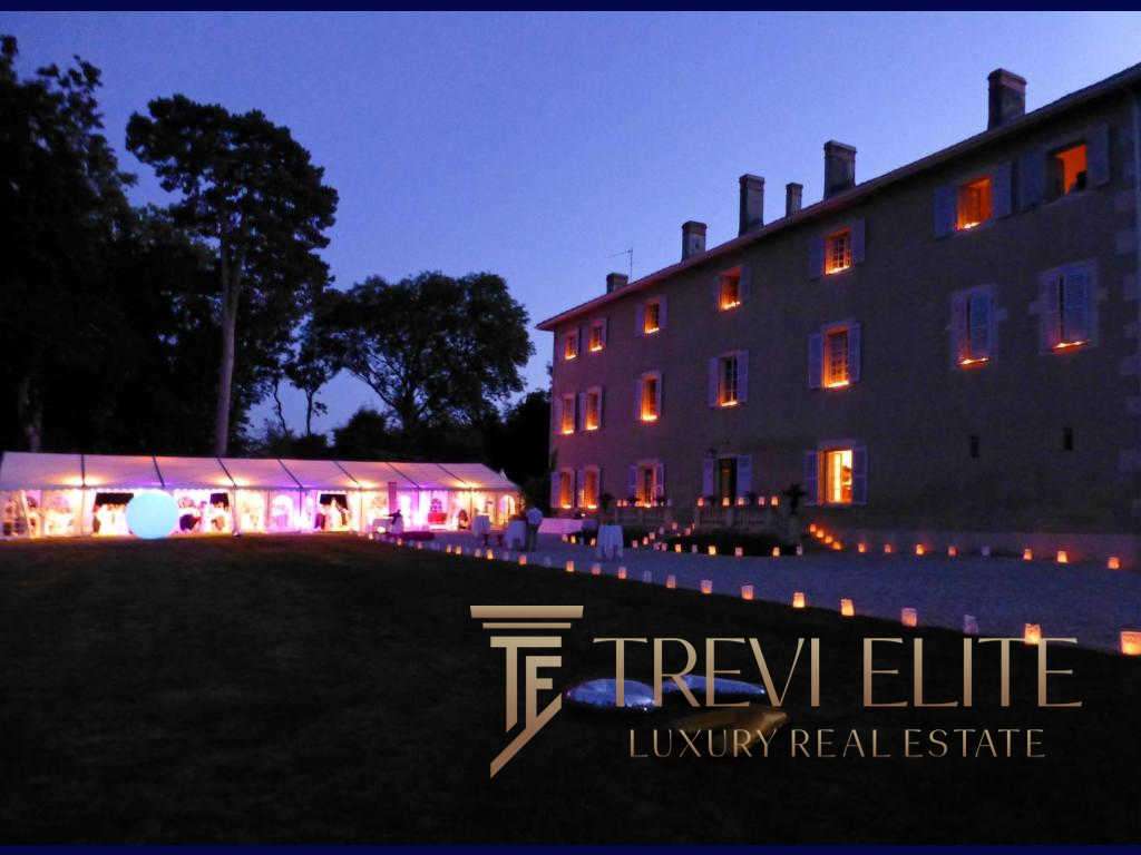 Элегантное ночное изображение роскошного особняка с подсвеченными окнами и зоной для мероприятий под звездным небом, рекламирующее агентство недвижимости Треви Элит.