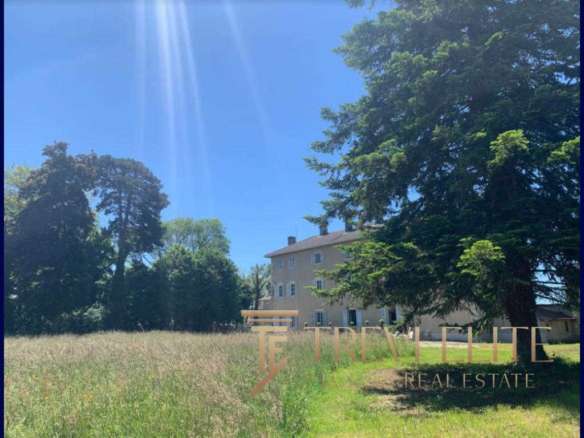 Многоэтажное жилое здание в окружении зеленых деревьев на фоне яркого голубого неба.