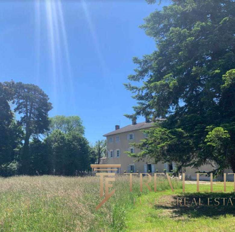 Многоэтажное жилое здание в окружении зеленых деревьев на фоне яркого голубого неба.